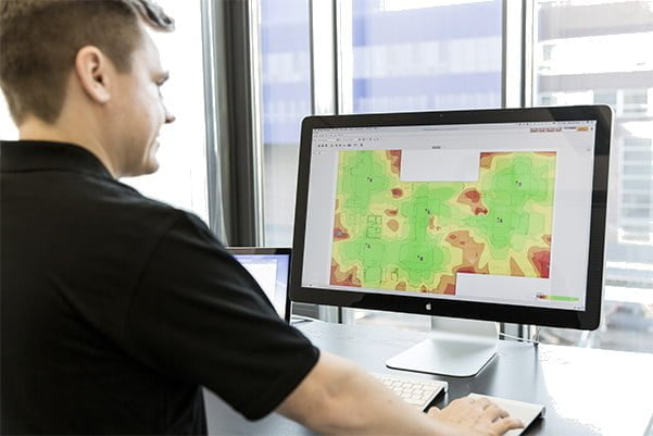Man in a black shirt looking at a computer screen that shows Ekahau site survey plan for Wi-Fi