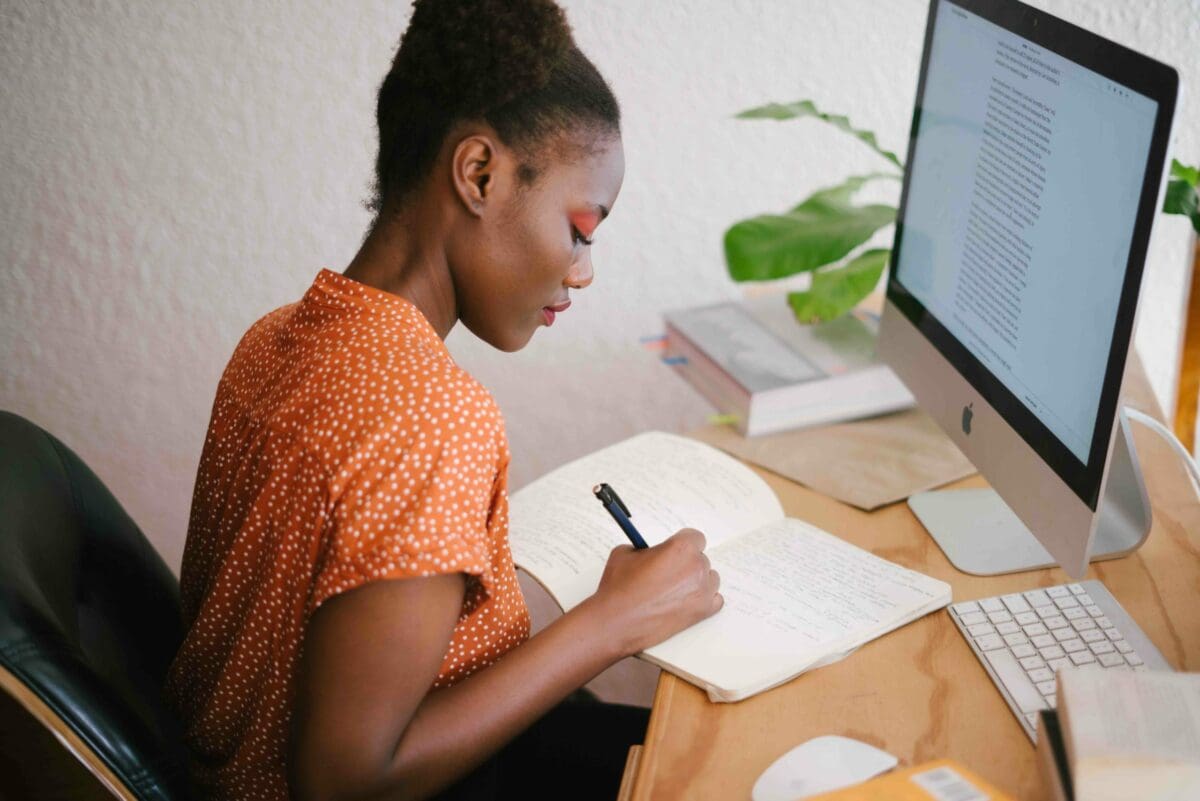 Woman in orange shirt working at her desk, in front of a computer