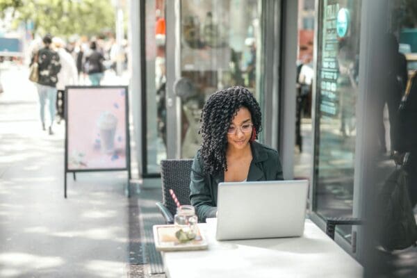 Woman wearing glasses working on a laptop at a cafe